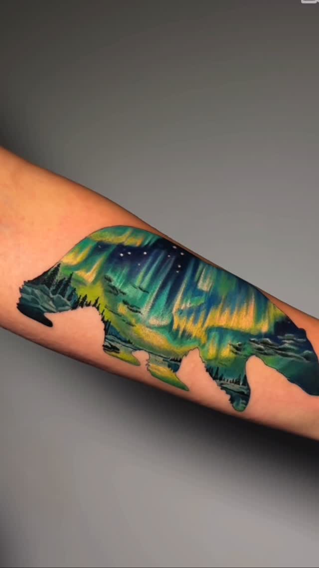 Bear and northern lights colour realism tattoo by Julia Luniko in Winnipeg