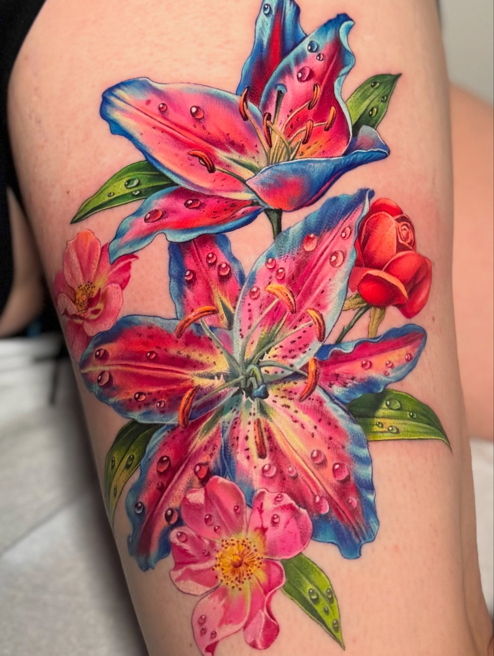 Rainbow-coloured floral lilies tattoo by Julia Luniko in Winnipeg