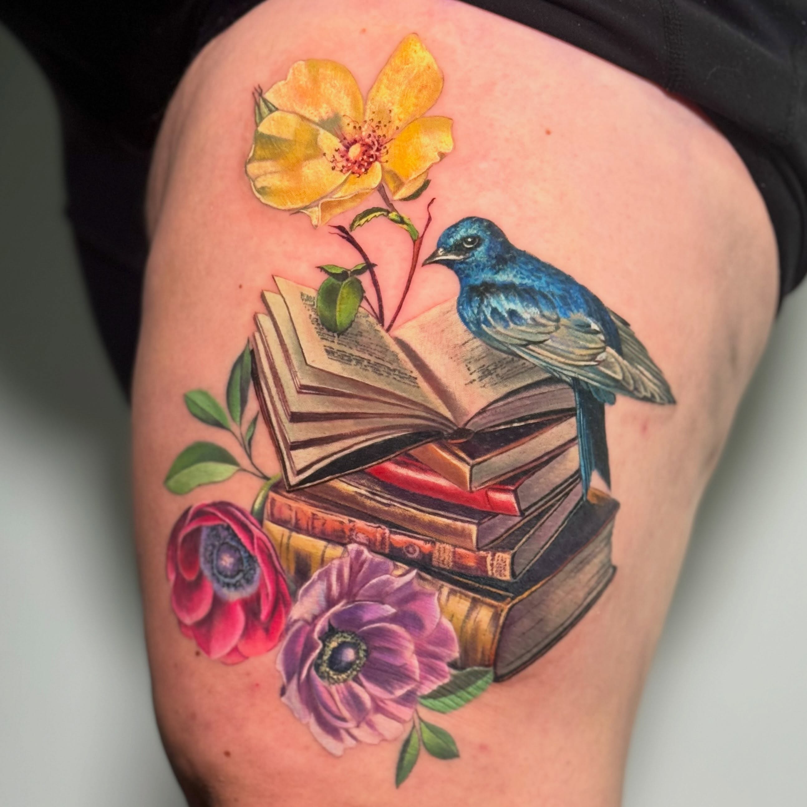 Blue swallow, books and colourful floral tattoo by Julia Luniko in Winnipeg
